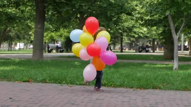 Κορίτσι με πολύχρωμα μπαλόνια που τρέχουν στα χέρια της μητέρας για να την αγκαλιάσει. Αργή κίνηση — Αρχείο Βίντεο