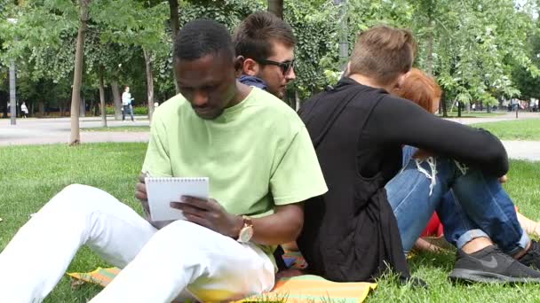 Afroamerikansk man skriver i en anteckningsbok i parken, slow motion — Stockvideo