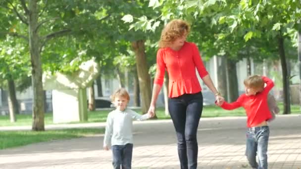 Matka a dvě malé děti, chůzi na cestě, drželi se za ruce s úsměvem — Stock video