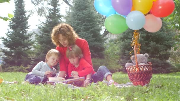 Mamma och dotter läser en bok i parken — Stockvideo