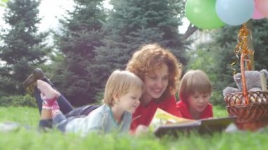 Mutlu anne ve güzel kızı parkta bir kitap okuma