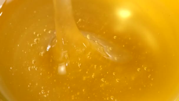 Usando colher para mel na tigela, pegá-lo, close, macro — Vídeo de Stock