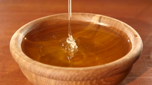 Принимая мед с помощью ложки в деревянной чаше, течет вниз — стоковое видео