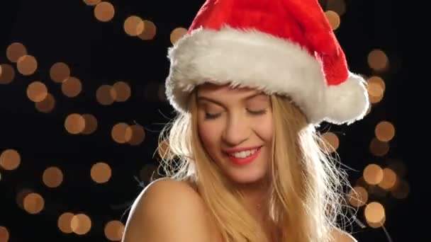 Belle blonde sexy en bonnet de Noël, isolée sur noire, gros plan, bokeh — Video