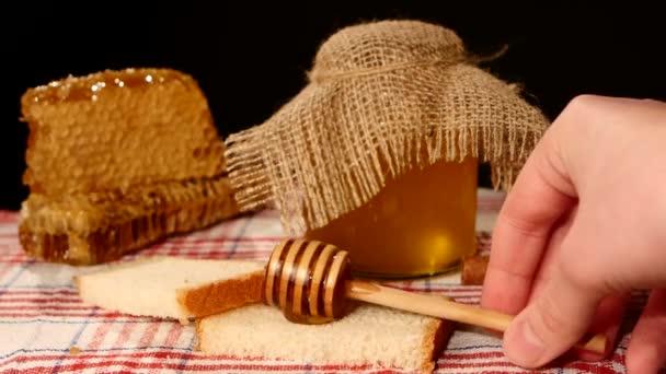 Honiglöffeltropfer, Glas mit Stiel über Toastbrot gießen, Wabe auf Schwarz — Stockvideo