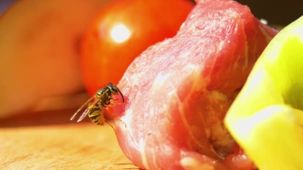 Een Wasp eet een deel van kip of varkensvlees voor barbecue op snijplank, close-up — Stockvideo