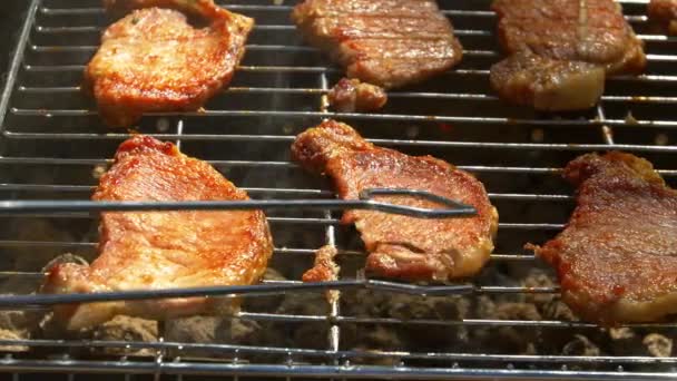 Bistecche di maiale alla griglia su fiamme e carboni, sul braciere, girare due fette, camma si muove a destra — Video Stock