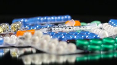 Bazı farklı kontraseptif hapları ve iki şırınga, rotasyon, yansıma, yakın çekim, siyah