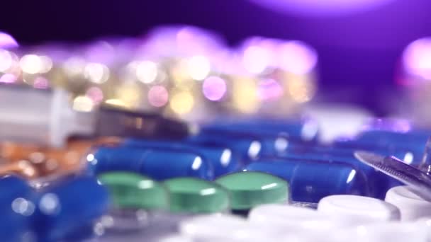 Agulha de seringa coloca em comprimidos diferentes, rotação, reflexão, close-up, em preto, luz traseira vermelho e azul — Vídeo de Stock