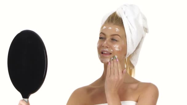 Sorridente bella giovane donna che applica la crema per il viso, bagno — Video Stock