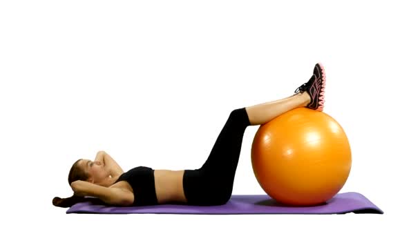 Mulher em roupa de ginástica excercising com uma bola pilates, fundo branco — Vídeo de Stock