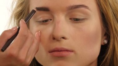 Kadın kaş şeklini kozmetik fırça kullanarak güzel çizer.