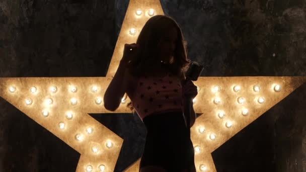 Woman singer with microphone, shining star in the background. close up. silhouette, slow motion — Stockvideo