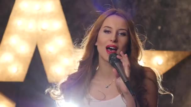 Sexy kobieta piosenkarka z mikrofonem, świecące gwiazdki w tle. z bliska — Wideo stockowe