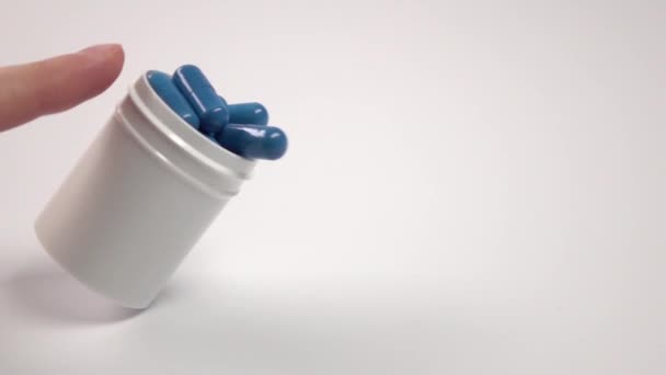 Pastillas azules cayendo de la botella de la píldora, en blanco, primer plano, cámara lenta — Vídeos de Stock