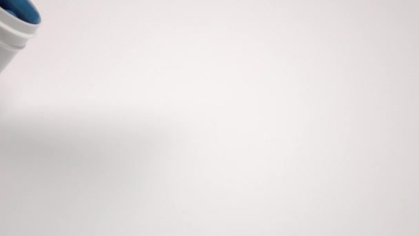 Beaucoup de pilules bleues tombent du flacon de pilule, sur blanc, gros plan, au ralenti 