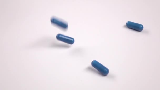 Синие таблетки падают на белое, замедленное движение, близко. — стоковое видео