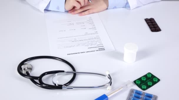 El médico termina de escribir un historial médico y un formulario de detección para el paciente, vista superior — Vídeo de stock