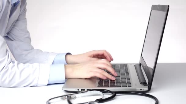 Dokter het typen van belangrijke informatie op de computer, wit — Stockvideo