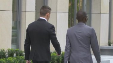 Ofis binasının yakınındaki sokakta yürüyen iki işadamı