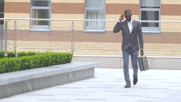 Retrato completo de un joven feliz caminando y hablando por teléfono móvil — Vídeos de Stock