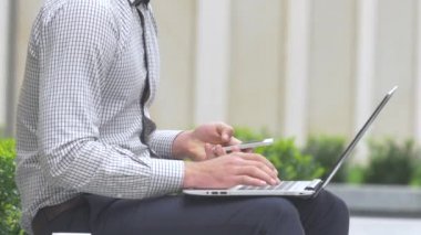 Dizüstü bilgisayarda yazarken cep telefonu tutan adamın kırpılmış eli