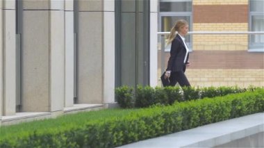 tablet bilgisayar ile iş kadını ofis binası etrafında gider. yavaş çekim, binanın dışında