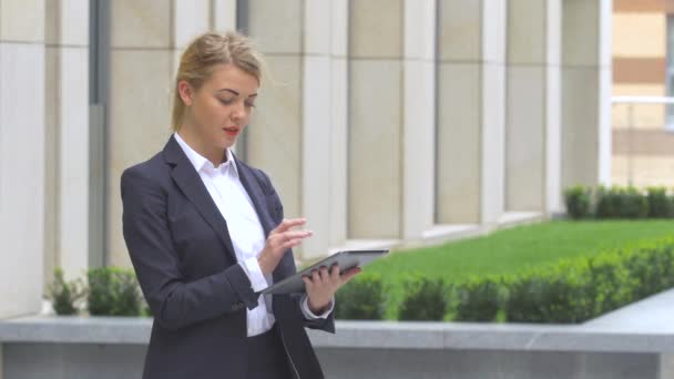 Elegant business woman with tablet computer near office building — Stock Video