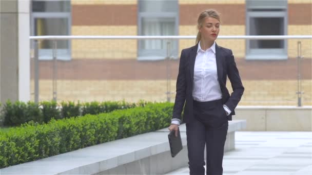 Mujer de negocios con Tablet PC va alrededor del edificio de oficinas. cámara lenta — Vídeos de Stock