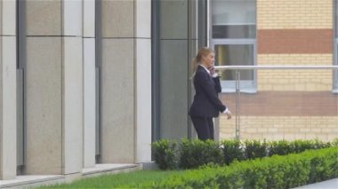 Başarılı kadın açık havada yürürken cep telefonuyla konuşuyor. yavaş çekim