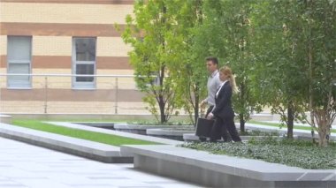 Bir iş merkezinin sokağında yürüyen iki iş arkadaşı. yavaş çekim