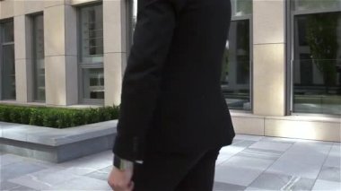 Genç işadamı binadan çıkıyor ve telefonda konuşuyor, ağır çekim.