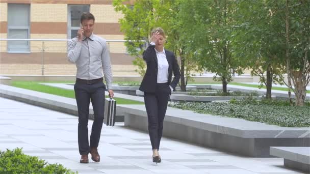 Dos exitosos colegas de negocios caminando por la calle de un centro de negocios. cámara lenta — Vídeos de Stock