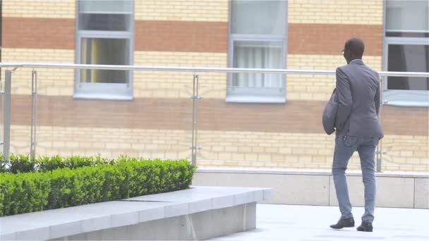 Un homme d'affaires afro-américain attrayant fait le tour du bâtiment, au ralenti — Video