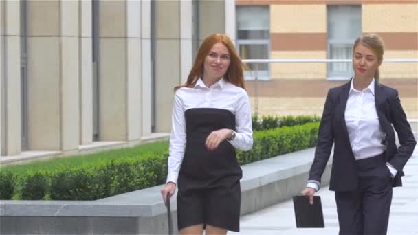 Deux jeunes femmes d'affaires marchant dans la rue près de l'immeuble de bureaux, au ralenti — Video