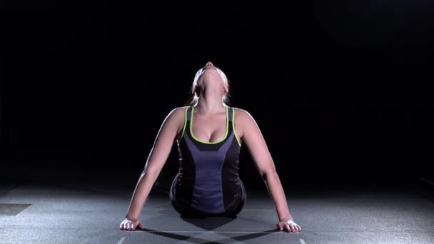 Vältränad kvinna stretching hennes rygg att värma upp, på svart — Stockvideo