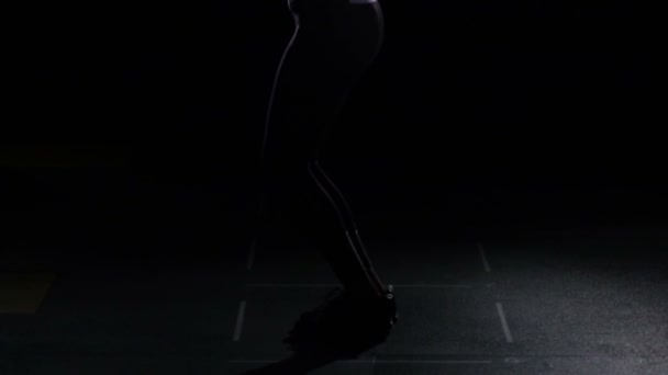 Mujer deportiva grave salta en la cuerda de salto, vista frontal, negro, cámara lenta — Vídeo de stock