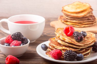 Tahta arka planda kırmızı çayla krep ve çilek