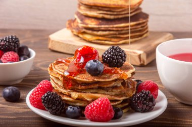 Tahta arka planda kırmızı çayla krep ve çilek