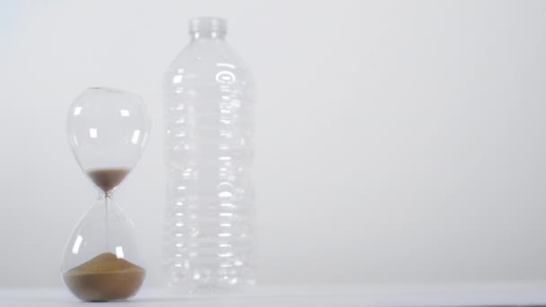 Eine Große Aufnahme Einer Leeren Sanduhr Neben Einer Einweg Plastikflasche — Stockvideo