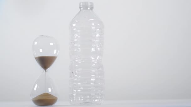 Eine Breite Aufnahme Einer Halbvollen Sanduhr Neben Einer Einweg Plastikflasche — Stockvideo