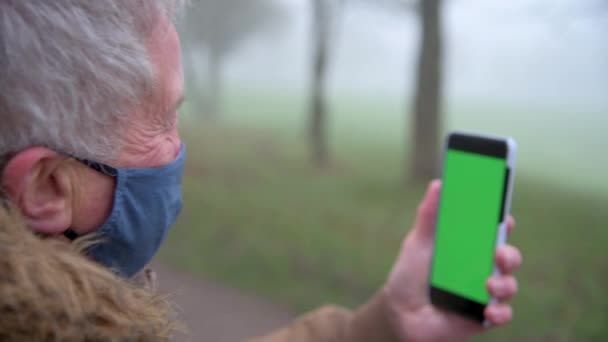 在寒冷的冬天 一位老人在一个雾蒙蒙的公园里打电话时肩膀上的近照 — 图库视频影像