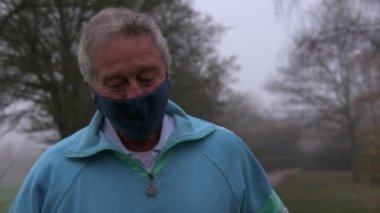 Yavaş çekim kıdemli adam alacakaranlıkta parkta koşuyor.