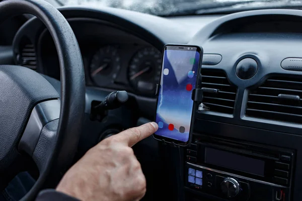 Arabadaki sürücü bir torpido kapağında bir araba tutacağının içine monte edilmiş akıllı bir telefon kullanıyor. Bulanık odak