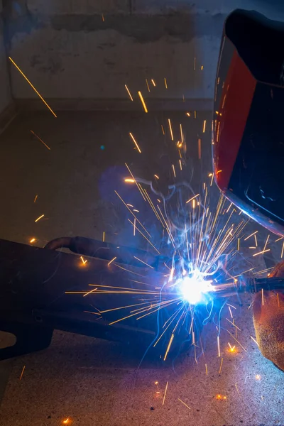 A welder performs semi-automatic arc welding at a manufacturing facility.