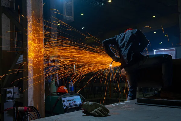 Manufacturing of steel pipes in one of the plant\'s workshops. Rotation of the angle grinder disc during operation. Bright sparks from metal cutting. Preparation of metal structures before welding.