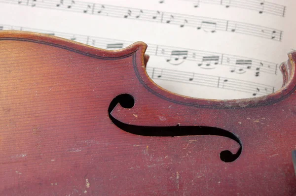 vintage brown violin music instrument on white sheet music close up