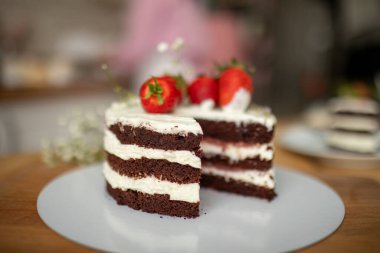 Bir pastanede çikolatalı pasta tutan bir pasta şefi, çilekle süslenmiş..