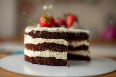 Bir pastanede çikolatalı pasta tutan bir pasta şefi, çilekle süslenmiş..