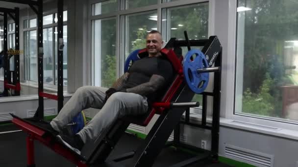 Muž ve sportovním oblečení s tetováním a oholenou hlavou říká něco na simulátoru Gakkova stroje. — Stock video